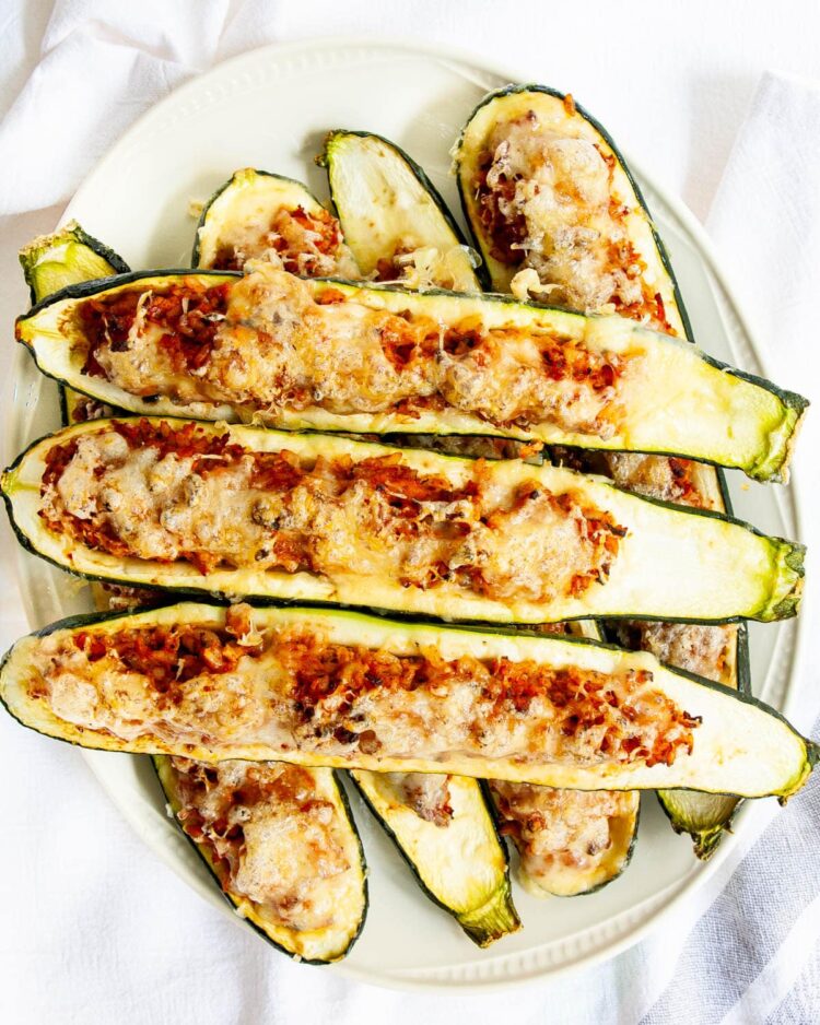 overhead shots of stuffed zucchini boats on a white serving platter