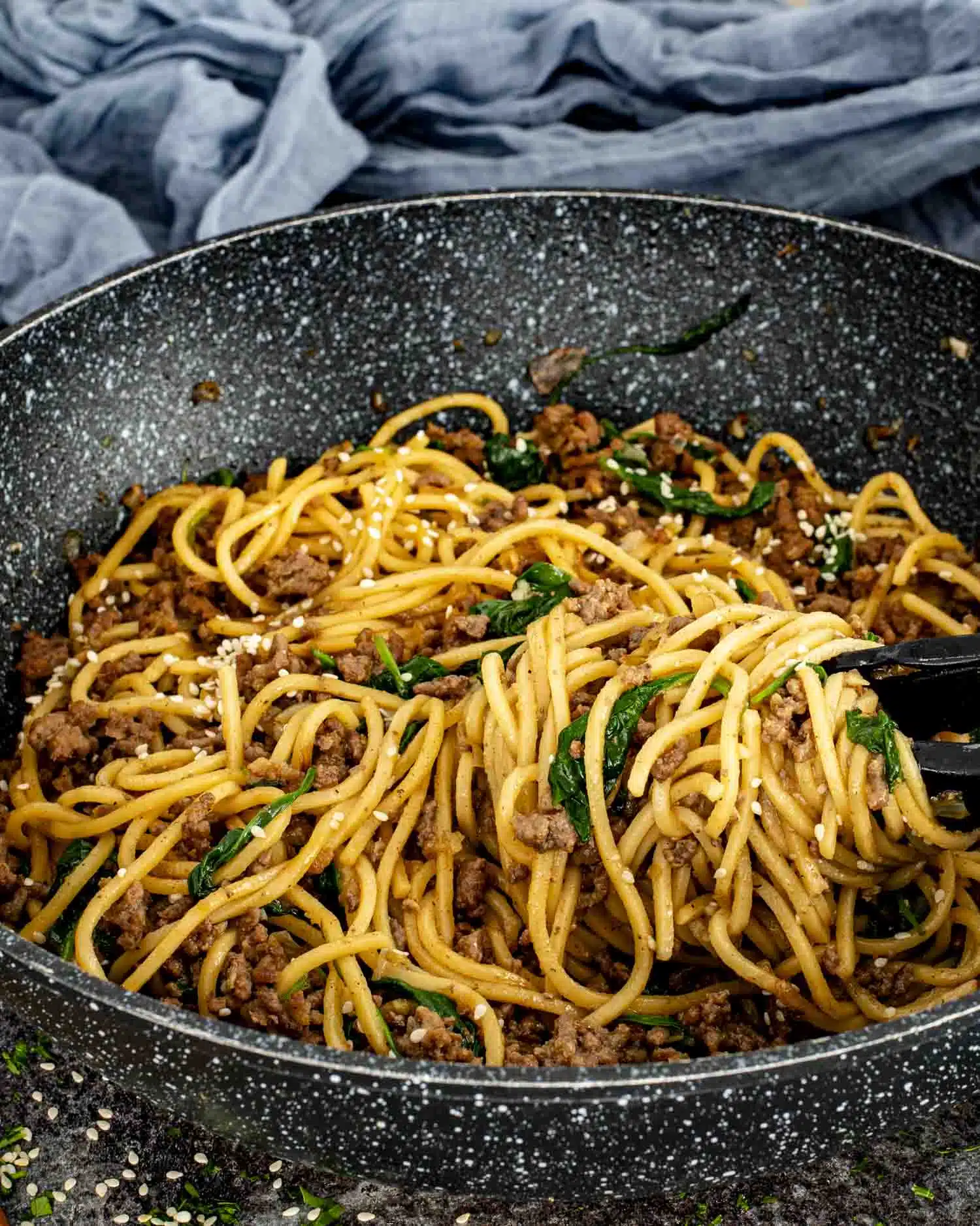 15 minute pork noodle stir fry in a wok garnished with sesame seeds.
