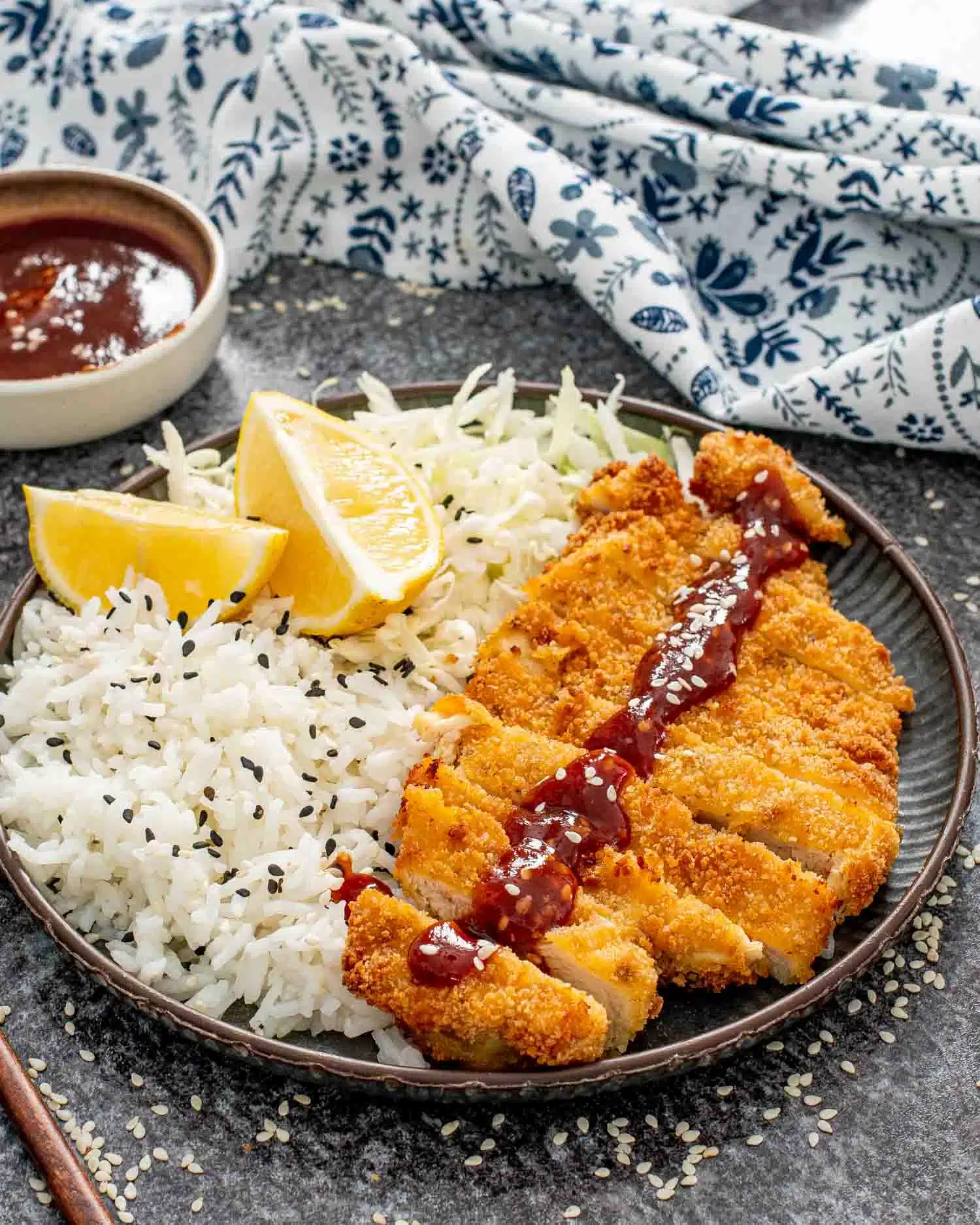 sliced up chicken katsu on a plate with rice and tonkatsu sauce.