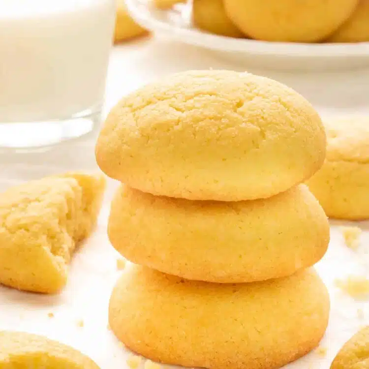 a stack of amish sugar cookies next to a glass of milk.