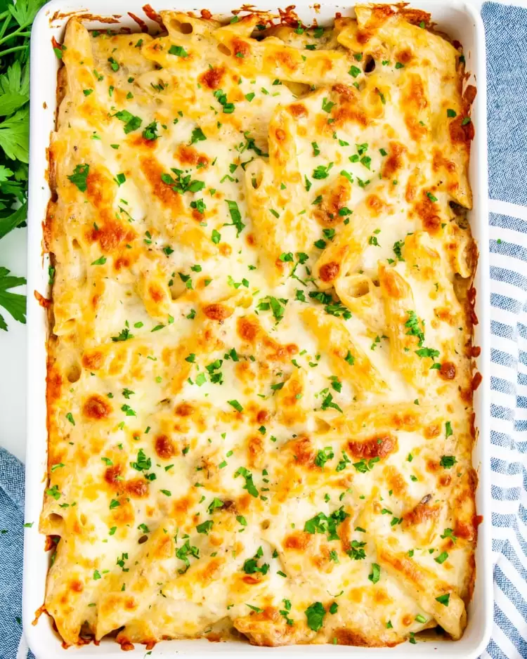 overhead shot of chicken alfredo bake in a casserole dish fresh out of the oven garnished with parsley