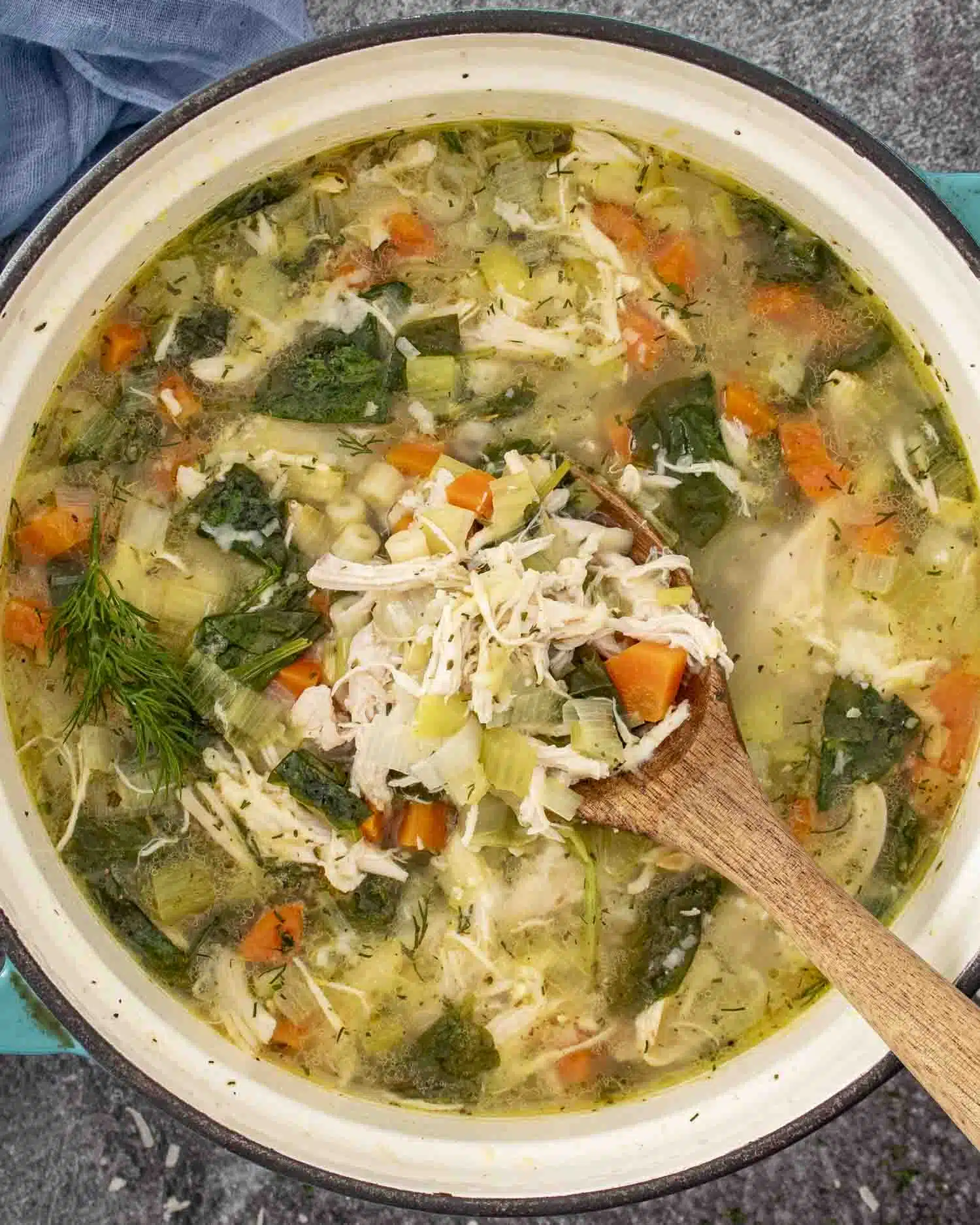 chicken and leek soup in a pot with a wooden spoon inside.