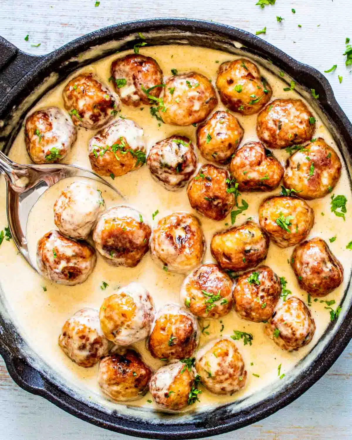 chicken meatballs in alfredo sauce in a skillet.