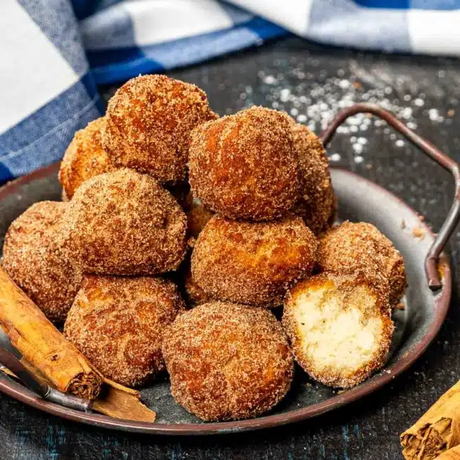 a metal plate with stacked cinnamon sugar donuts holes.