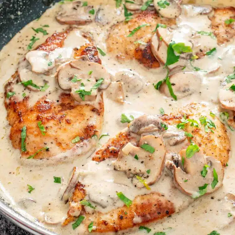 freshly made creamy garlic mushroom chicken in a skillet garnished with parsley.