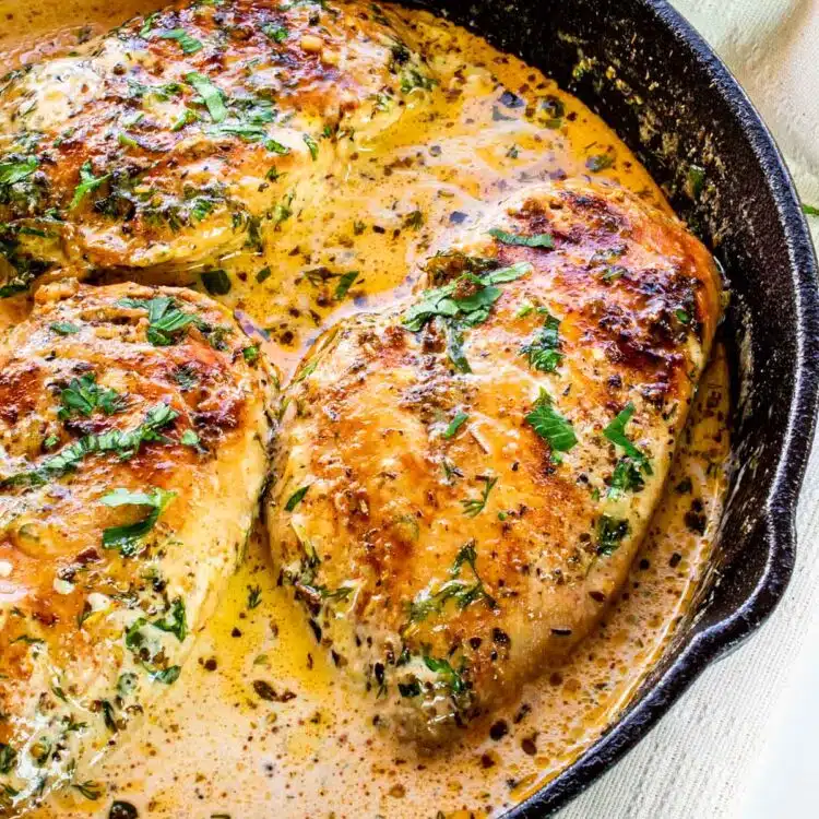 creamy herb chicken breasts in a black skillet.