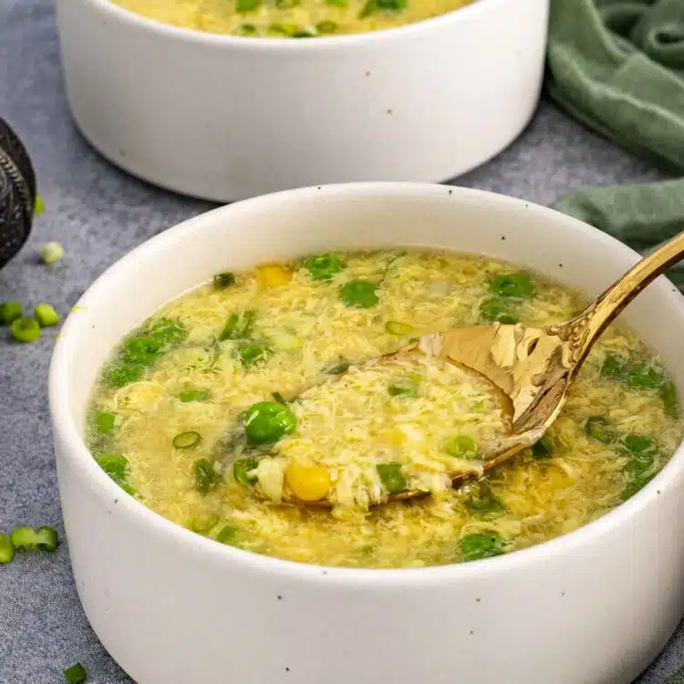 a bowl of freshly made egg drop soup with a spoon inside.
