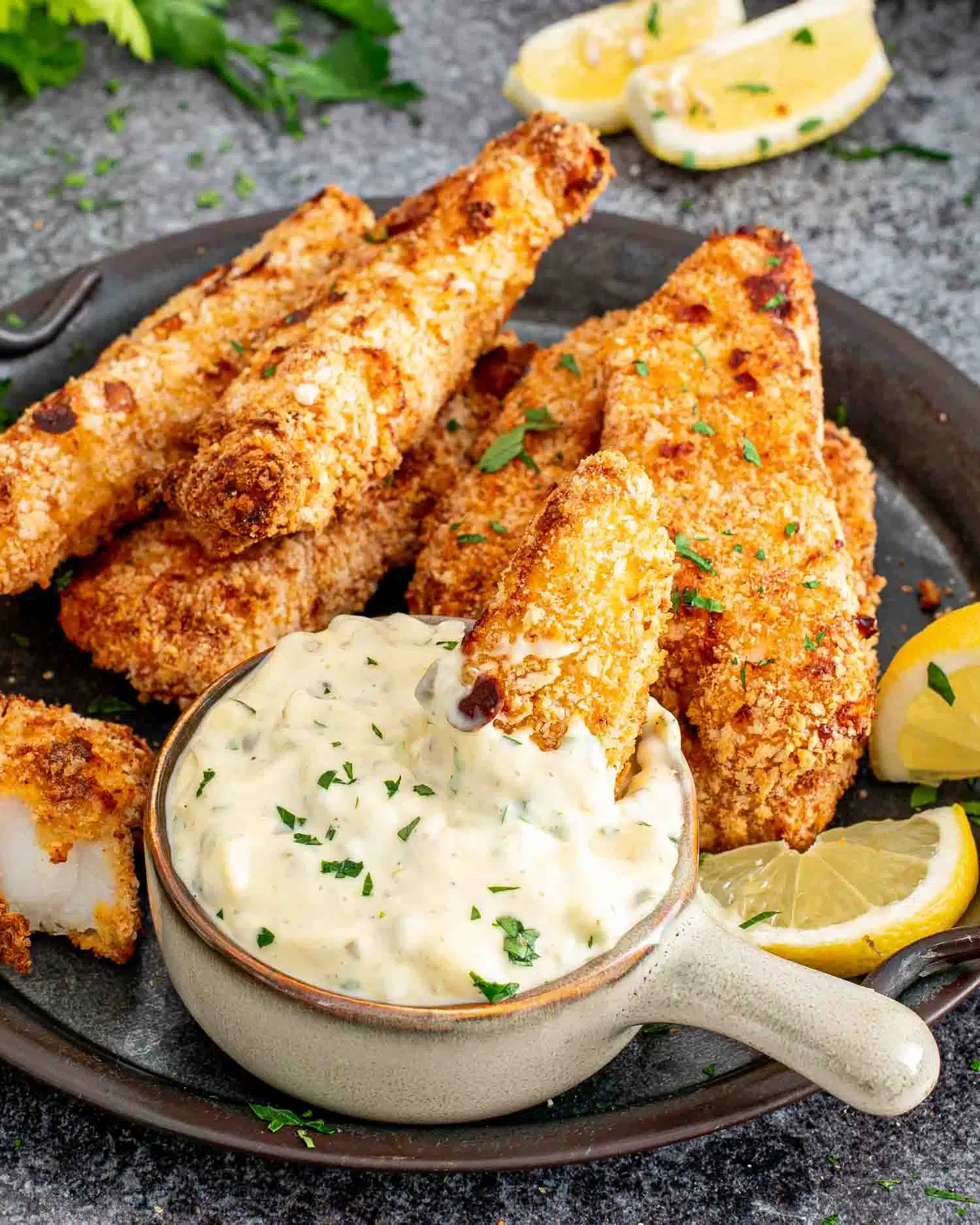 air fried fish sticks on a platter with a bowl with tartar sauce in it.