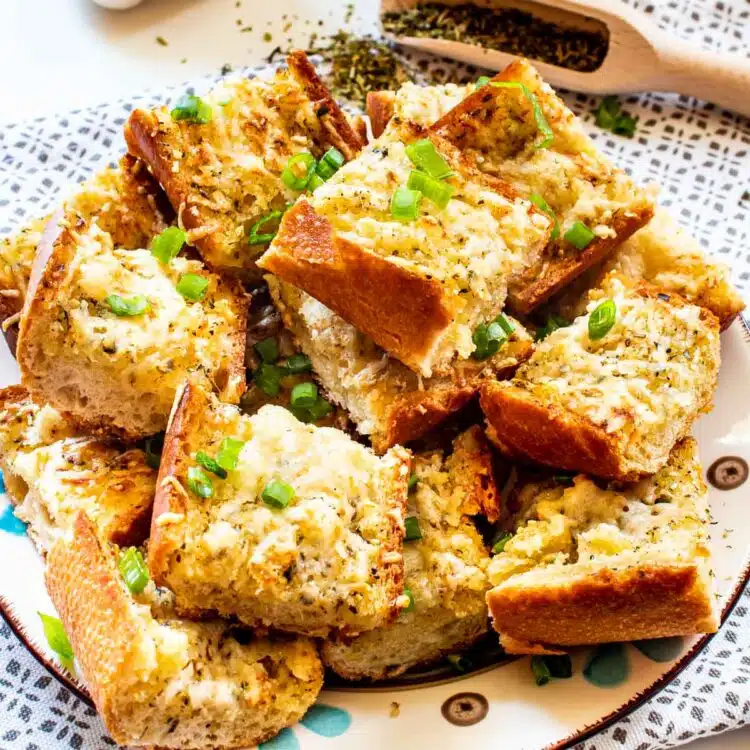garlic bread cut up in slices on a plate garnished with green onions.