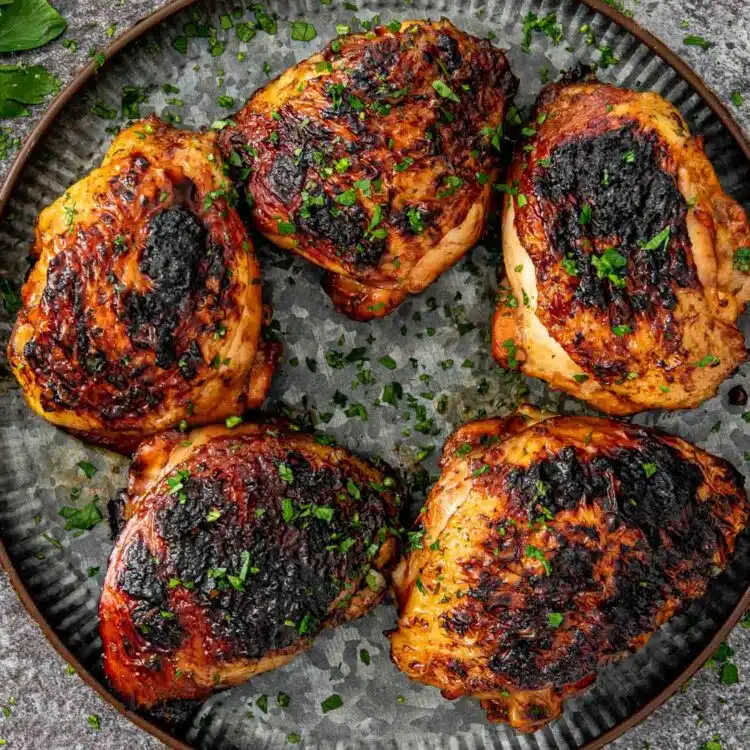 huli huli chicken thighs on a platter garnished with a bit of parsley.