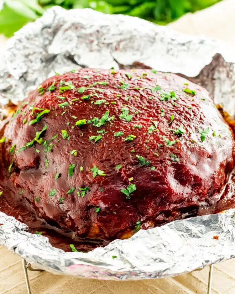 side view shot of meatloaf topped with ketchup and garnished with parsley 