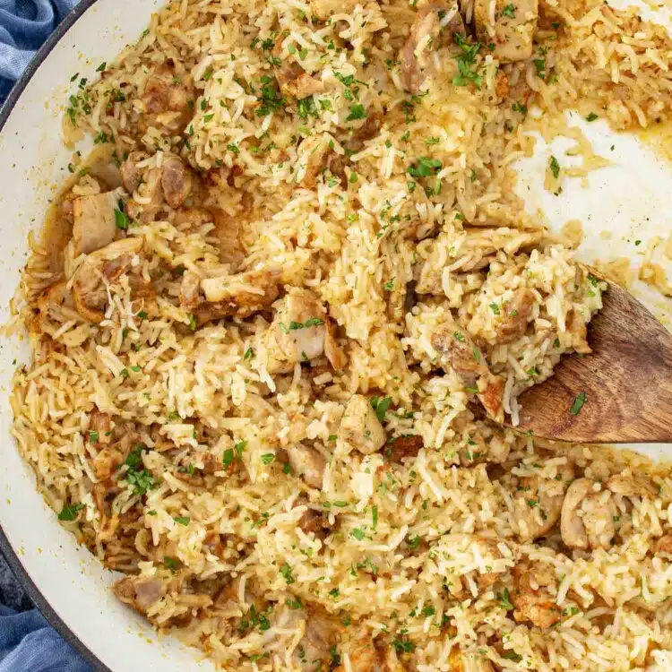 garlic butter chicken and rice in a braiser garnished with parsley.