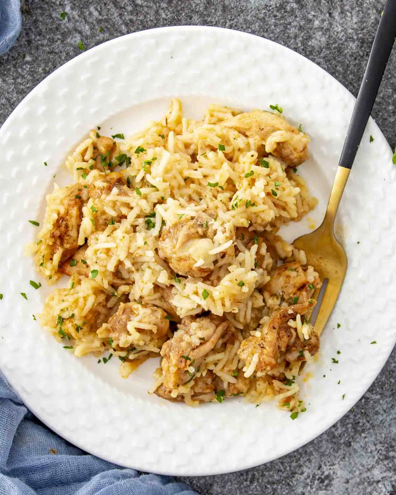 a serving of garlic butter chicken and rice on a white plate.