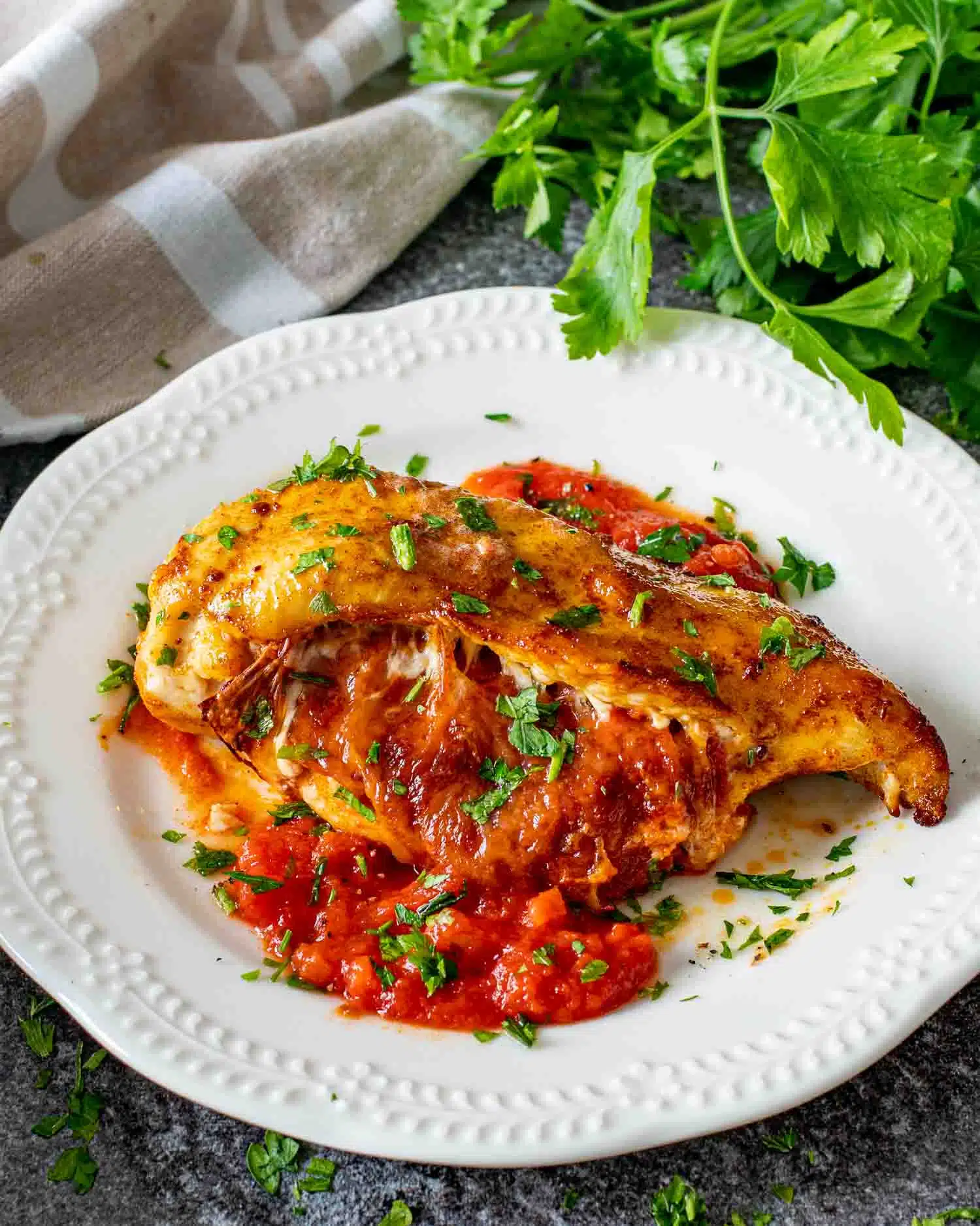 a pizza stuffed chicken breast on a plate garnished with parsley.