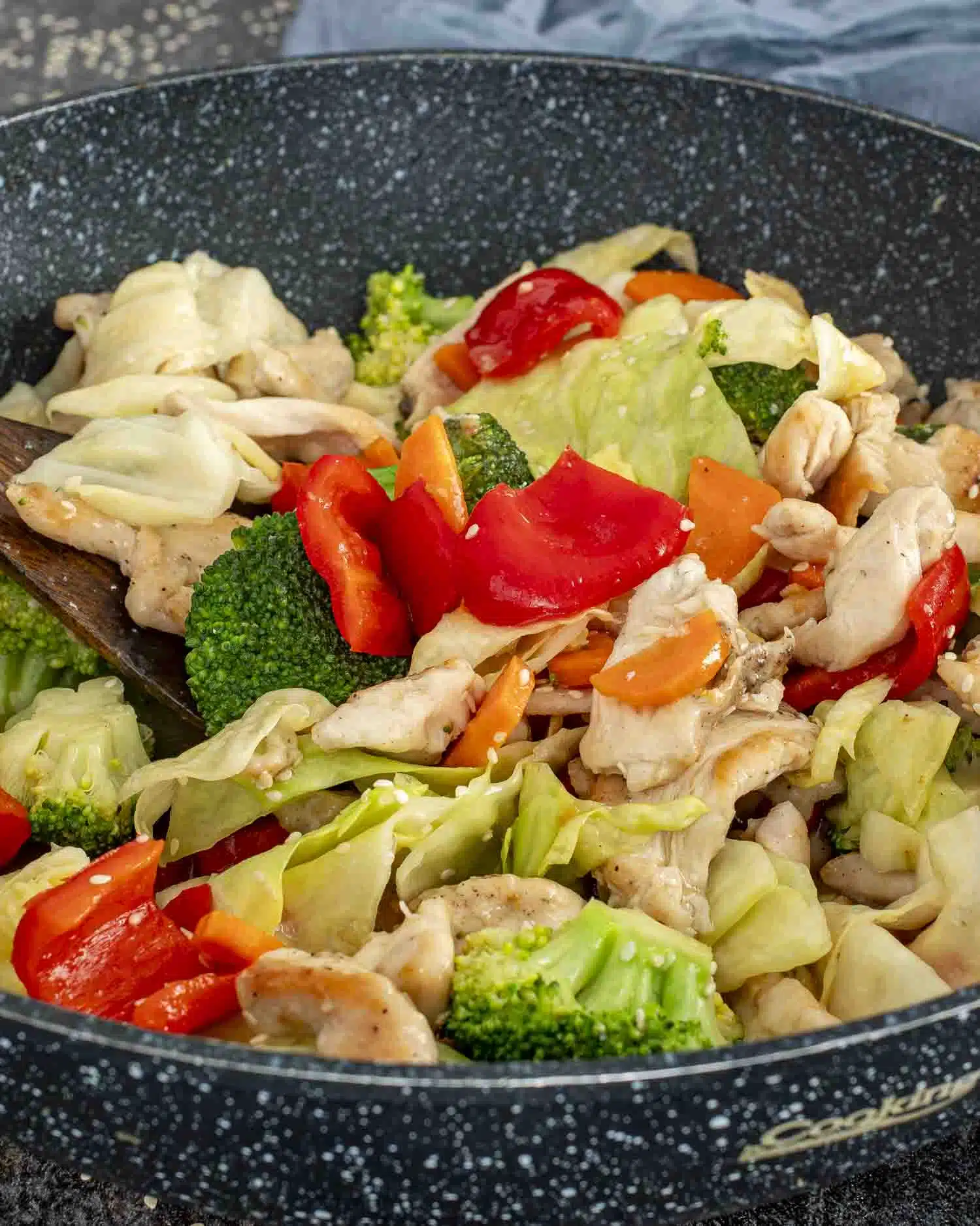stir fried chicken and veggies in white sauce in a wok, freshly made.