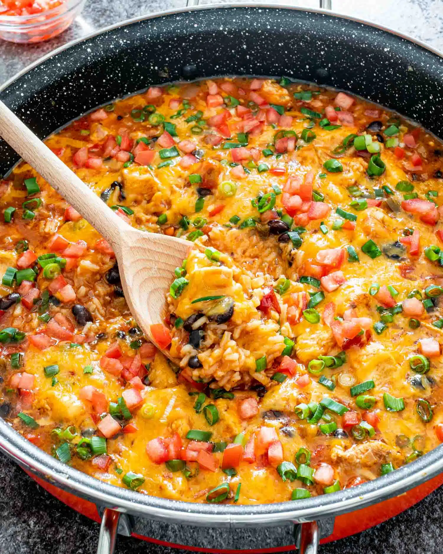 southwest chicken and rice in a skillet with a wooden spoon inside.