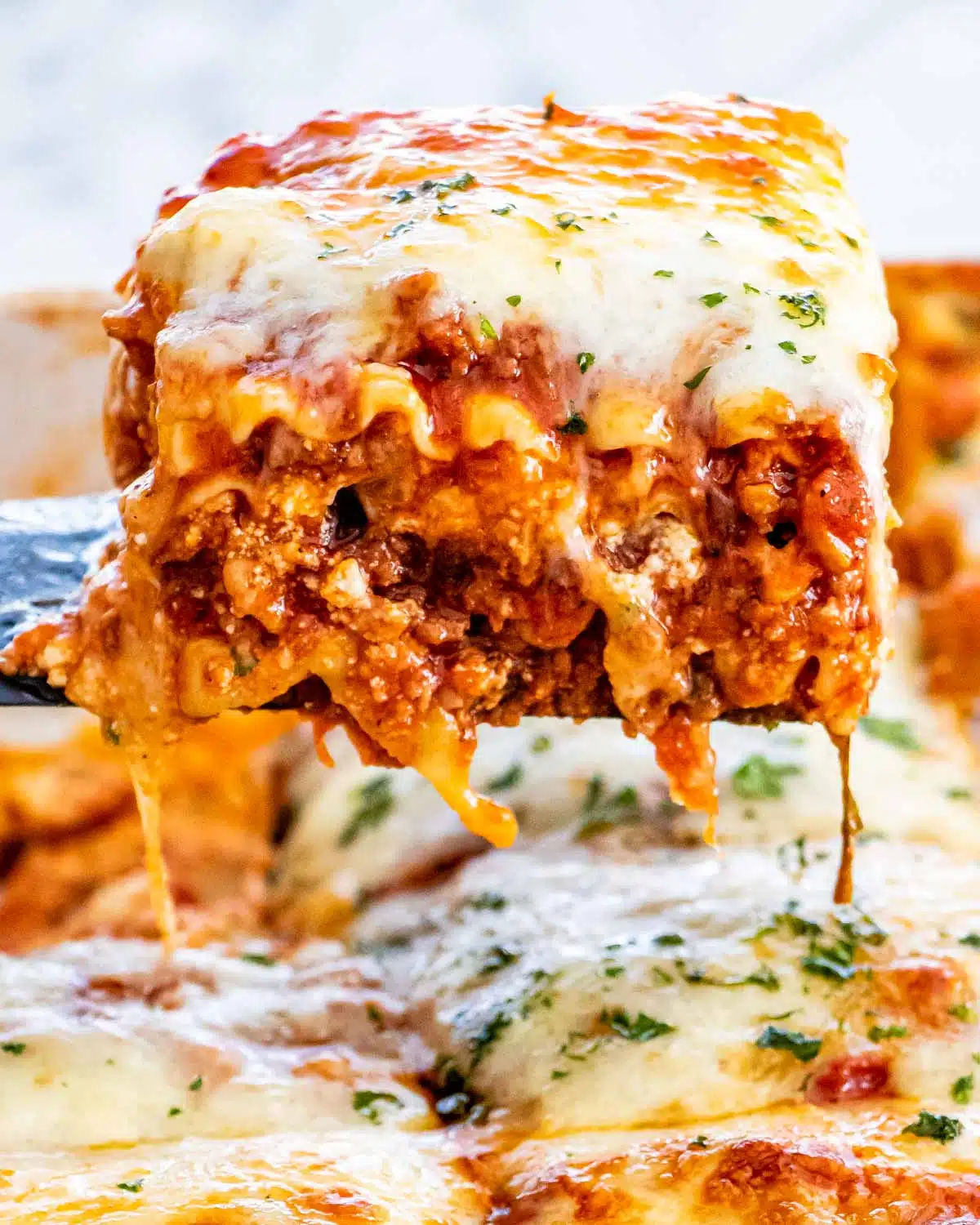 a spatula lifting a piece of lasagna from a casserole dish.