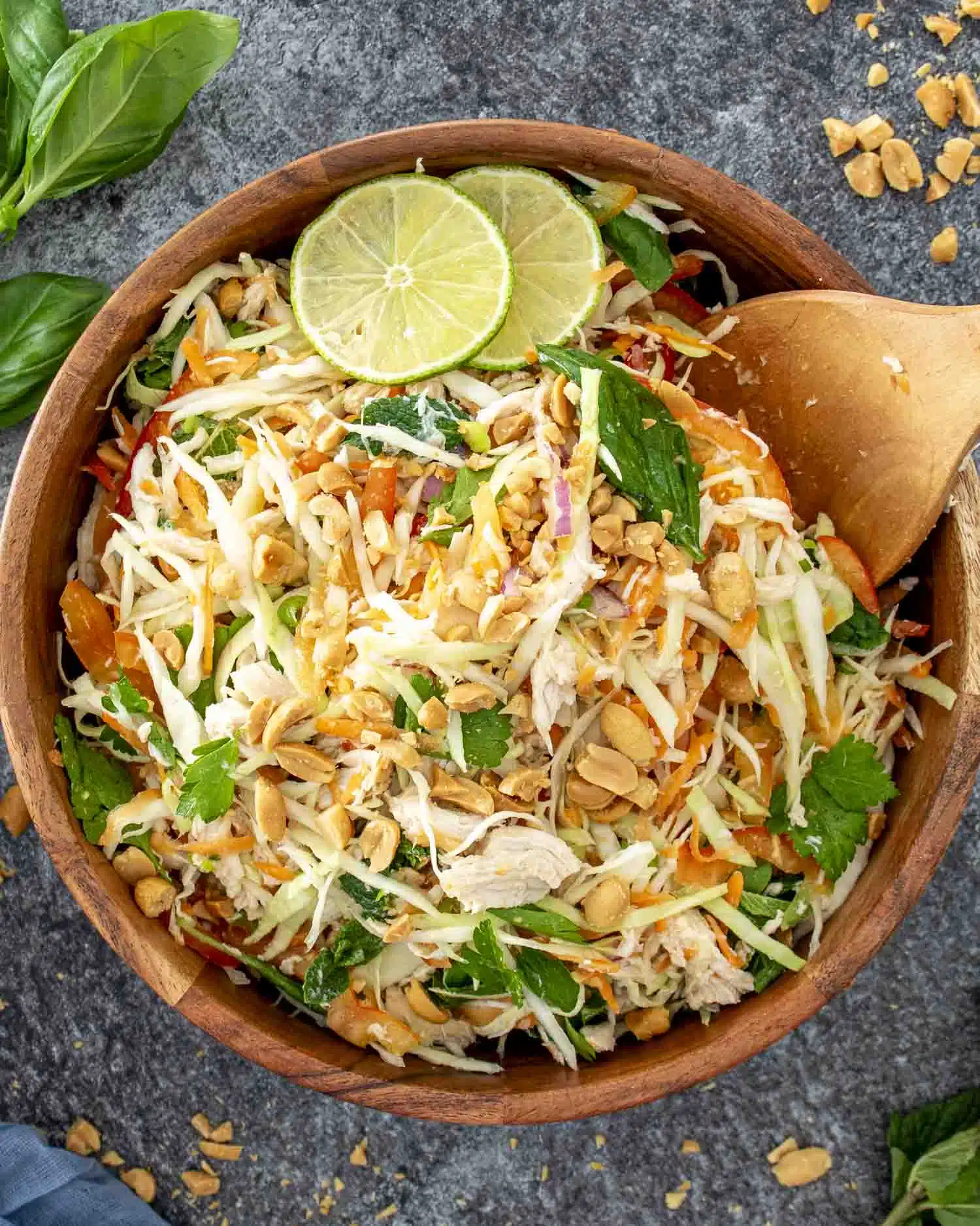 fresh vietnamese chicken salad in a wooden bowl garnished with 2 lime slices.