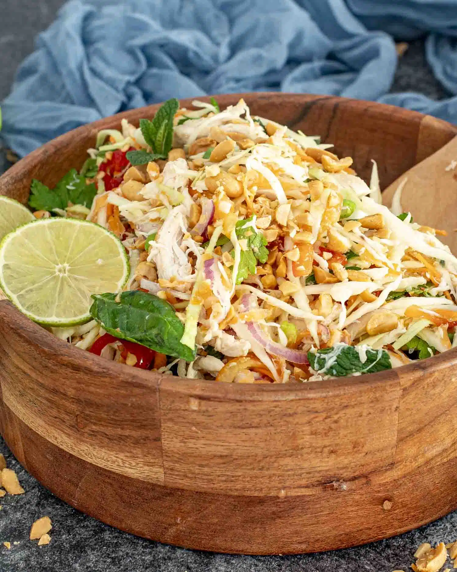 fresh vietnamese chicken salad in a wooden bowl garnished with 2 lime slices.