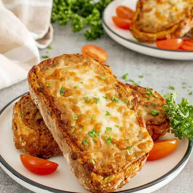 a couple slices of walsh rarebit on a white plate garnished with some parsley.