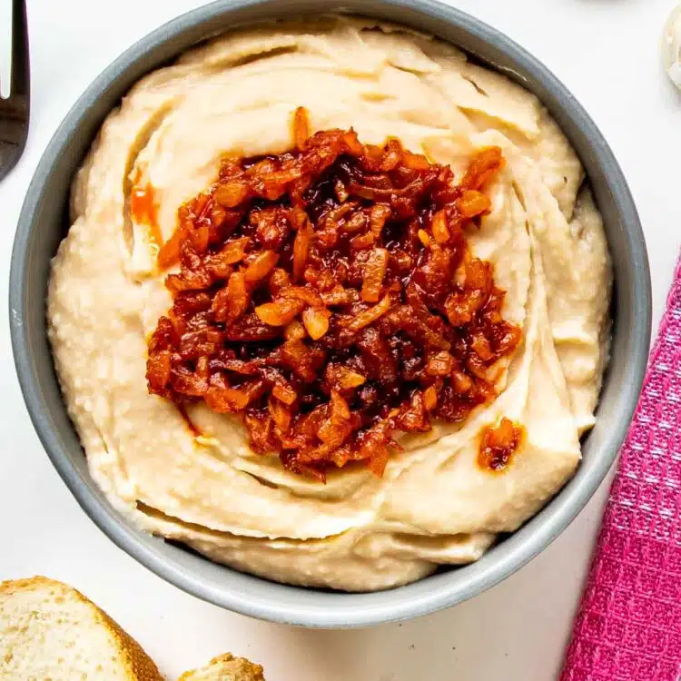 white bean dip with sauteed onions in a blue bowl.